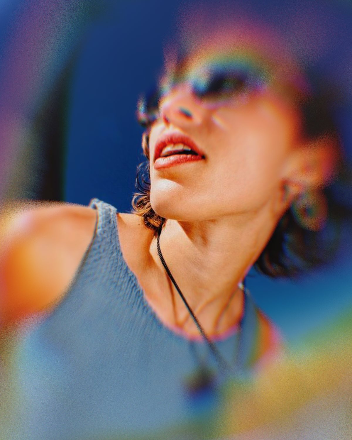 Prism lens effect on a portrait of a woman in sunglasses against a blue sky, made with the Ghost Lens filter in Filter Archive (Tunnel preset)