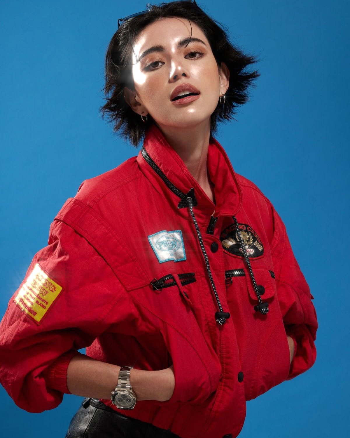 Star filter effect on a portrait of a woman in a red jacket on a blue background, made with the Starlight filter in Filter Archive (Soft Bloom preset)